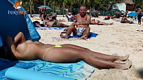 Tomando el sol en topless en la playa para ser observada por otros hombres